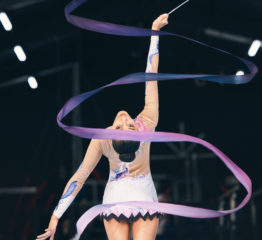 Ribbon gymnastics, flexible woman and dancing in performance, training and competition from the bac