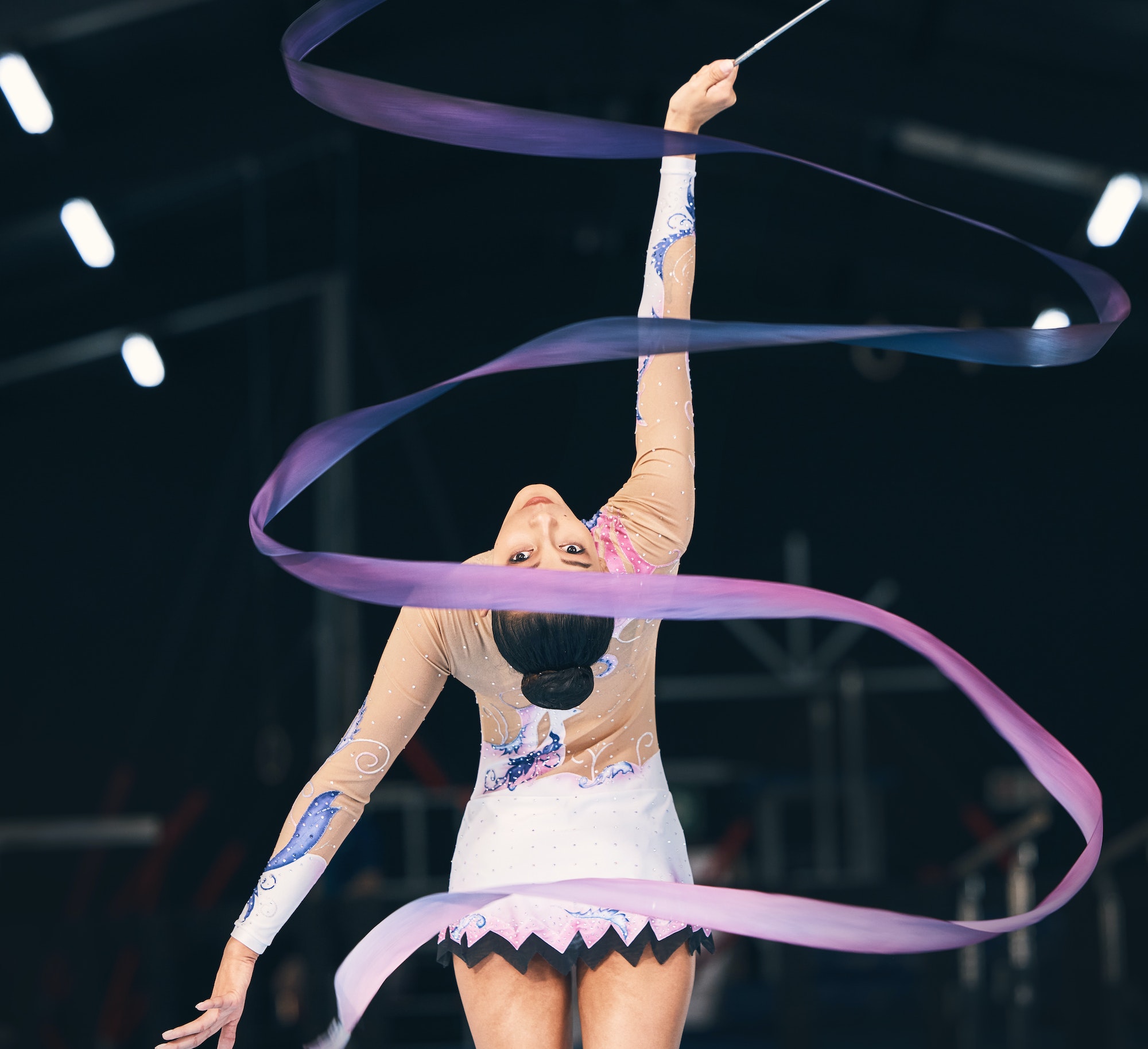 Ribbon gymnastics, flexible woman and dancing in performance, training and competition from the bac