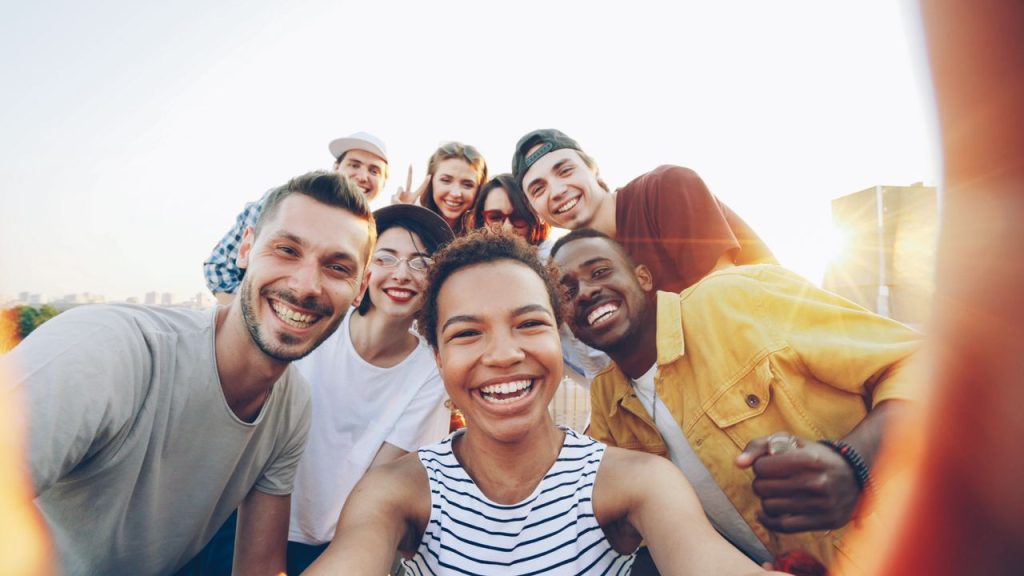 A diverse group of friends taking a joyful selfie outdoors during sunset.
